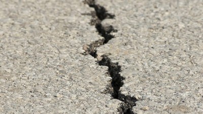 En spricka som går genom asfalt på marken.