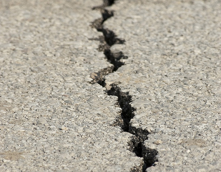 En spricka som går genom asfalt på marken.