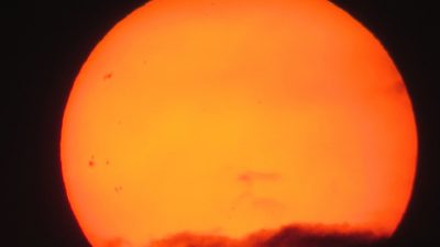 Solen. Den är orange med lite mörka moln framför i nederkant.