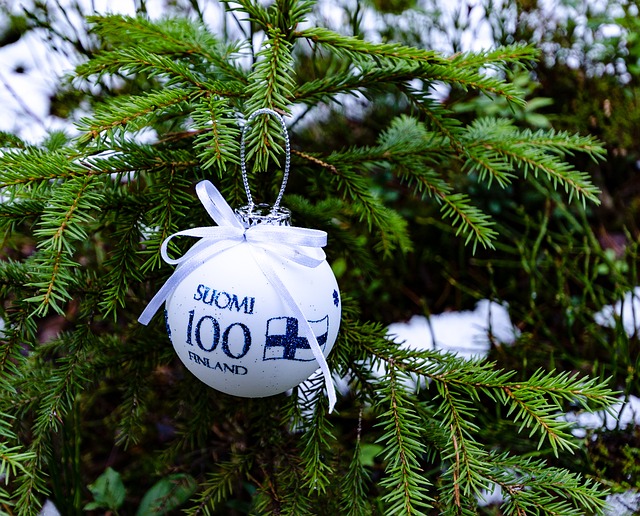 En vit julgranskula där det står Finland 100 på finska och svenska