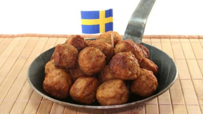 En liten stekpanna med en hög av köttbullar i. Istucket bland köttbullarna är en liten svensk flagga.