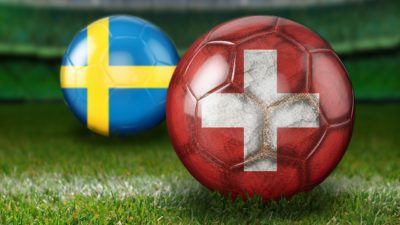två fotbollar en med sveriges flagga och en med schweiz