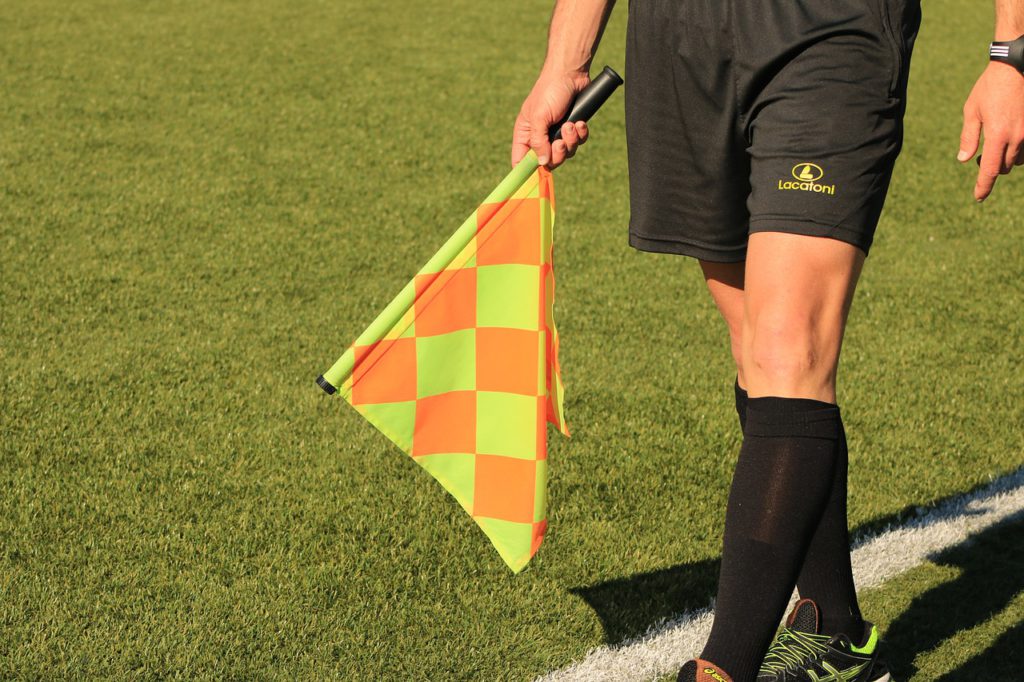 En fotbollsdomare meden flagga.
