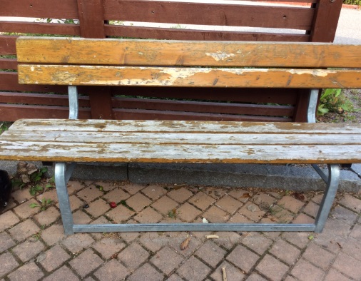 Närbild på en sliten bänk utomhus.