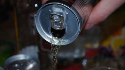 Foto på någon som häller upp energidryck i ett glas.