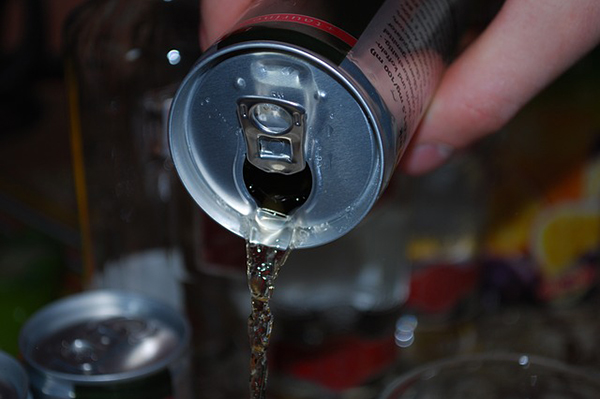 Foto på någon som häller upp energidryck i ett glas.