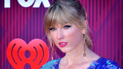 Taylor Swift på en gala. Hon har mycket smink, hår i tops och en klänning gjord av stora paljetter.