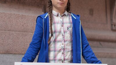 Greta Thunberg håller en skylt där det står skolstrejk för klimatet.