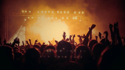 Foto från en konsert. Händerna i luften och ljus från scenen.