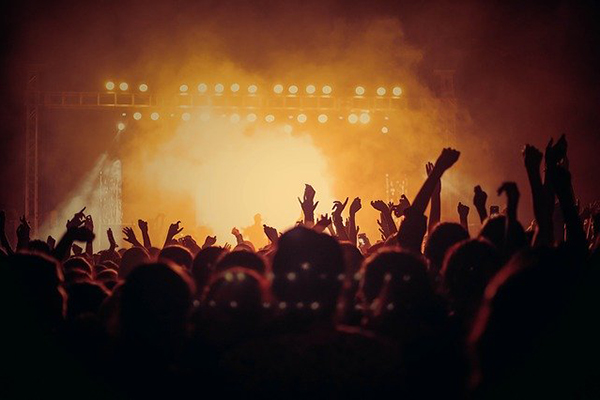 Foto från en konsert. Händerna i luften och ljus från scenen.