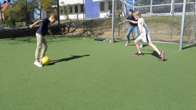 Tre elever som spelar fotboll.