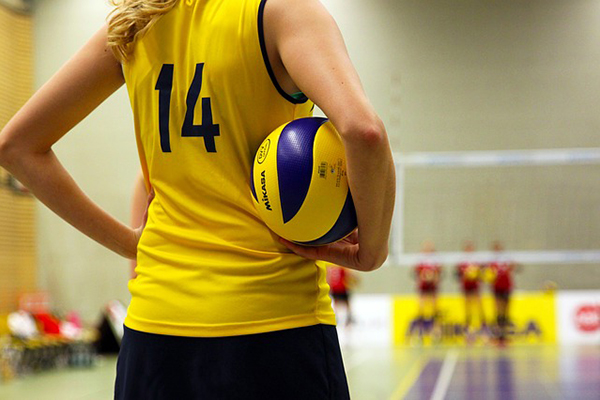 En tjej på en volleybollplan inomhus.