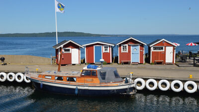 Foto på en båt och fiskebodar vid Hanö