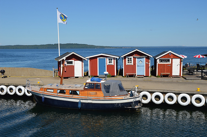 Foto på en båt och fiskebodar vid Hanö