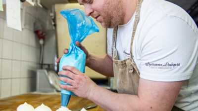 Martin Persson spritsar grädde på semlor.