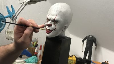 Björn målar detaljer på ett vitt huvud med röda läppar.